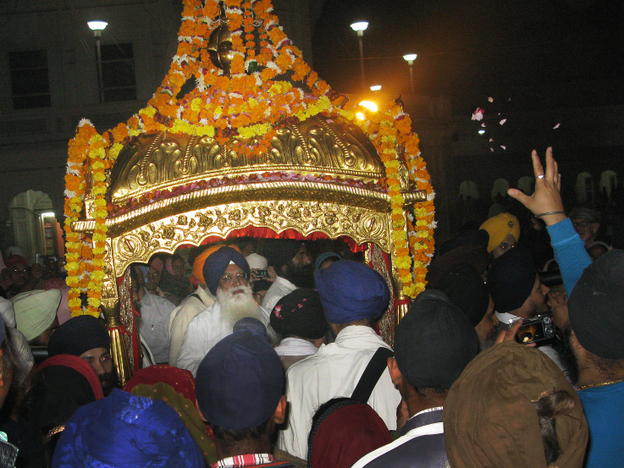 Devotees reach out to the gilded litter that carries the Sikh holy book, the Guru Granth Sahib, to the Golden Temple in Amritsar.