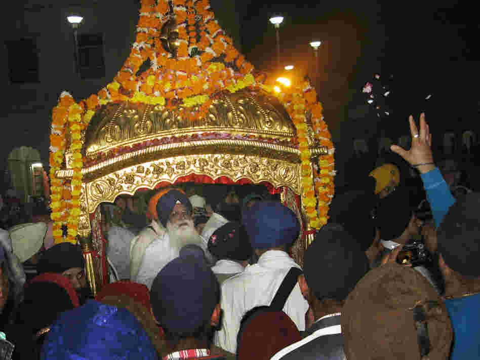 Devotees reach out to the gilded litter that carries the Sikh holy book, the Guru Granth Sahib, to the Golden Temple in Amritsar.