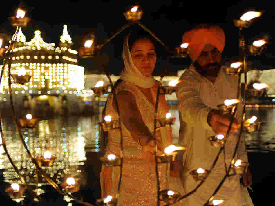 Sikh devotees Puneet Kaur (left) and Gurmeet Singh light lamps as they pay their respects at the Golden Temple in October. Temple authorities are considering installing solar panels for the lighting system to make it more environmentally friendly. 