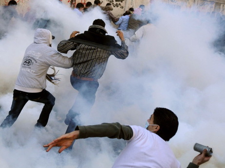 An Egyptian protester prepares to hurl a tear gas canister back at security forces as others run for cover earlier today in Cairo's Tahrir Square. An Egyptian protester prepares to hurl a tear gas canister back at security forces as others run for cover earlier today in Cairo's Tahrir Square.
