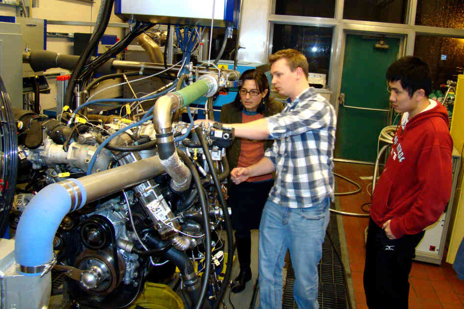 Professor Anna Stefanopoulou (left) examines a V8 internal combustion engine with students Jacob Larimore and Xinfan Lin at the University of Michigan's Automotive Research Center. The researchers model engine performance to improve efficiency. Professor Anna Stefanopoulou (left) examines a V8 internal combustion engine with students Jacob Larimore and Xinfan Lin at the University of Michigan's Automotive Research Center. The researchers model engine performance to improve efficiency.