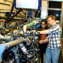 Professor Anna Stefanopoulou (left) examines a V8 internal combustion engine with students Jacob Larimore and Xinfan Lin at the University of Michigan's Automotive Research Center. The researchers model engine performance to improve efficiency.