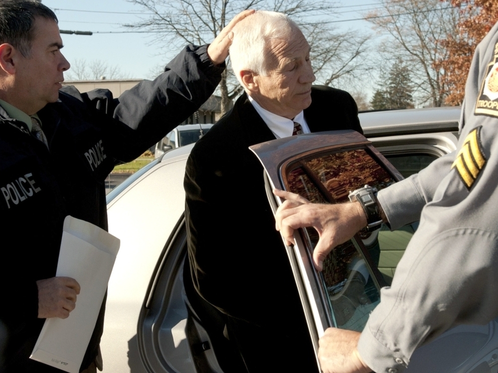 Gerald "Jerry" Sandusky, center, is placed in a police car in Bellefonte, Pa. on Saturday, Nov. 5.