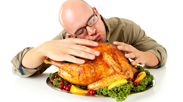 A man embracing a turkey.