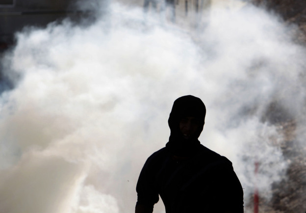 Anti-government protester runs away from tear gas fired by riot police Wednesday in A'ali, Bahrain. 