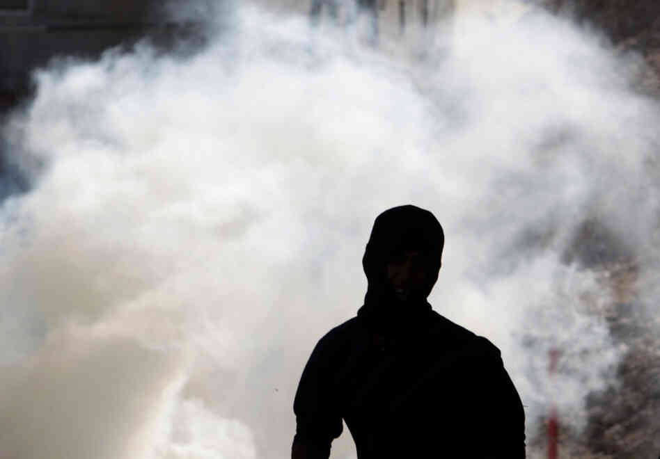Anti-government protester runs away from tear gas fired by riot police Wednesday in A'ali, Bahrain. 