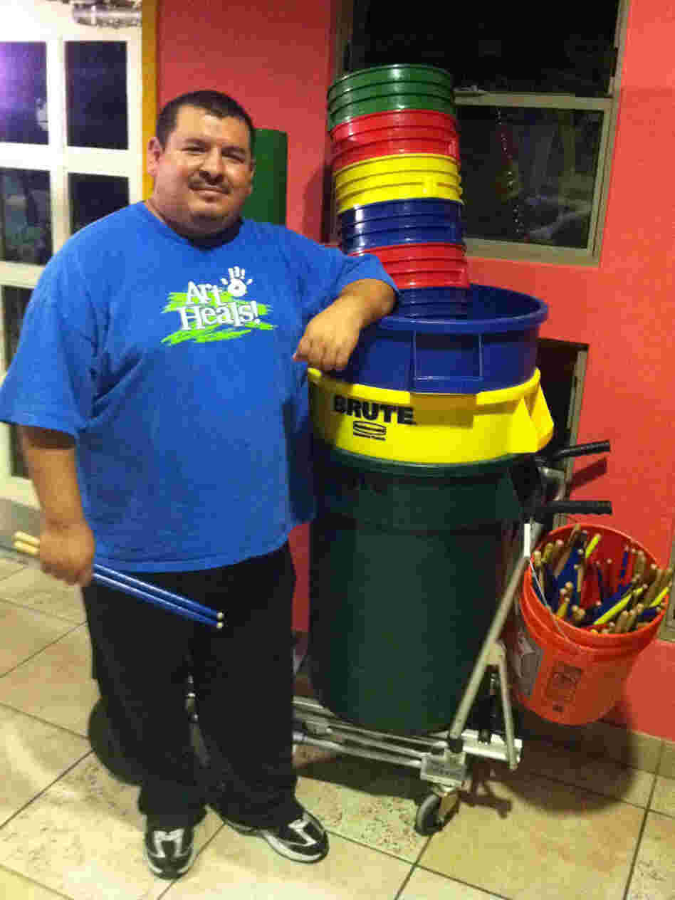 Mario Barela stands next to the supplies he uses for his percussion class. He teaches the fundamentals of drumming to children in a Phoenix domestic violence shelter.