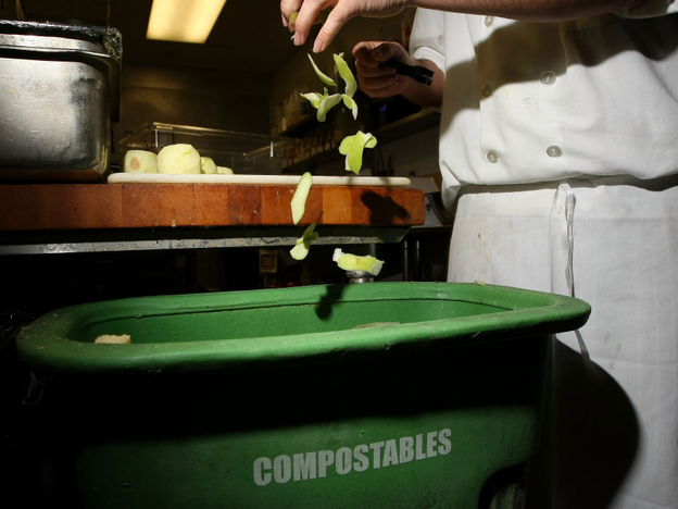 A prep cook drops apple skins into a food scrap recycling container in San Francisco. 