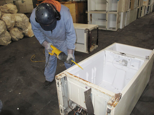 A worker at Jaco Environmental saws into an old refrigerator to remove the insulating foam in the fridge's walls. The 10 pounds of foam contains about 1 pound of CFC 11 gas, a very powerful greenhouse gas. Jaco sends the foam and other CFCs in the fridge's compressor to be destroyed.