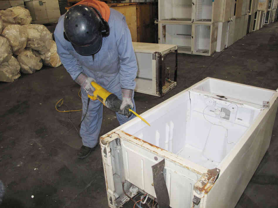 A worker at Jaco Environmental saws into an old refrigerator to remove the insulating foam in the fridge's walls. The 10 pounds of foam contains about 1 pound of CFC 11 gas, a very powerful greenhouse gas. Jaco sends the foam and other CFCs in the fridge's compressor to be destroyed.