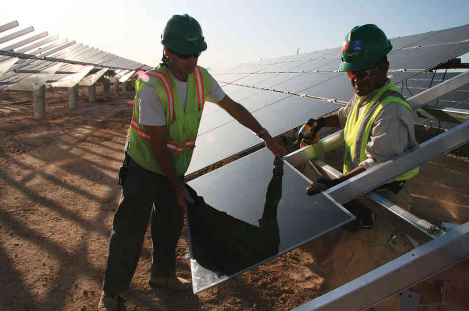 Workers install solar panels at the Soaring Heights Communities at Davis-Monthan Air Force Base outside Tucson, Ariz.