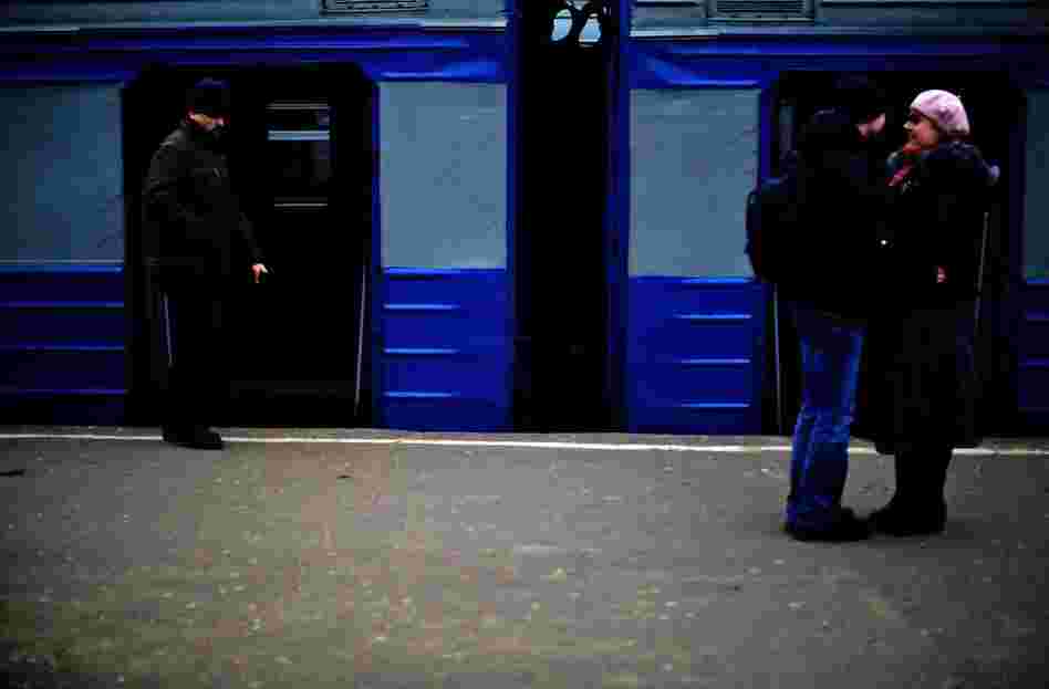 Passengers wait for a local train at a small station.