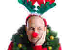 A man bedecked in Christmas attire and looking miserable.