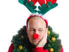 A man bedecked in Christmas attire and looking miserable.