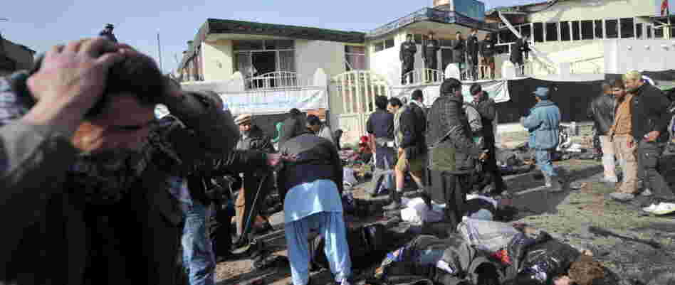 A man grieves as others try to help victims and remove bodies from the scene in Kabul earlier today (Dec. 6, 2011) after a suicide bomb exploded in a crowd of Shiite worshipers.