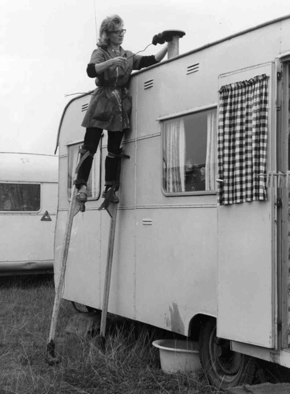 Stilt walker Joy Sloan cleans the chimney of a trailer belonging to a member of British showman Billy Smart's circus in 1963. 