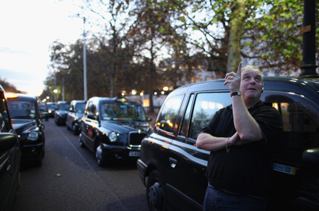 A taxi driver stands outside his cab in London, England. A taxi driver stands outside his cab in London, England.
