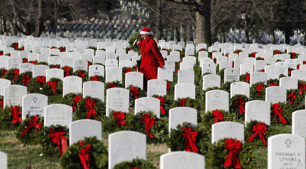Volunteer Pati Redmond of Frederick, Md., helps to lay holiday wreaths over the graves of fallen soldiers at Arlington National Cemetery in Washington Saturday.