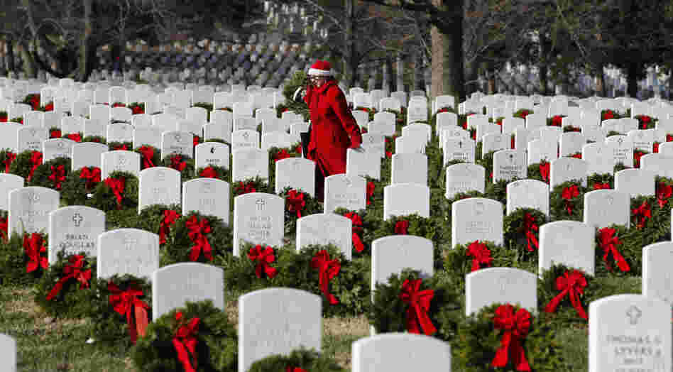 Volunteer Pati Redmond of Frederick, Md., helps to lay holiday wreaths over the graves of fallen soldiers at Arlington National Cemetery in Washington Saturday.