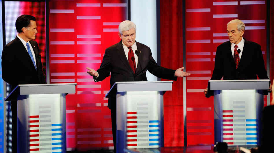Former House Speaker Newt Gingrich speaks while former Massachusetts Gov. Mitt Romney and U.S. Rep. Ron Paul look on during the ABC News GOP presidential debate on Saturday in Des Moines, Iowa.