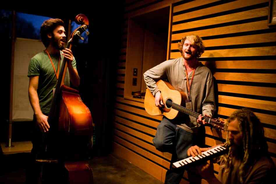 From left: Farmers Nate Kraus-Malett, Max Godfrey and Steven "Shepsi" Eaton prepare to play their instruments at a nighttime dance at the conference.
