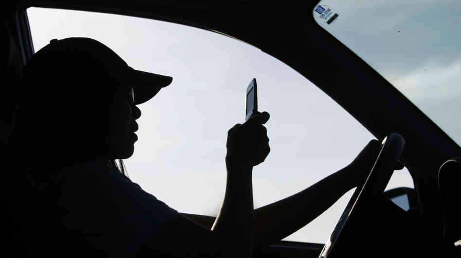 A driver uses a cellphone in Maine, which has laws that ban people under 18 from using cellphones behind the wheel and bar all drivers from texting. A driver uses a cellphone in Maine, which has laws that ban people under 18 from using cellphones behind the wheel and bar all drivers from texting.