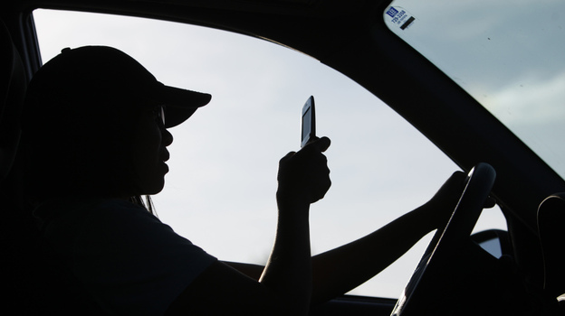 A driver uses a cellphone in Maine, which has laws that ban people under 18 from using cellphones behind the wheel and bar all drivers from texting. A driver uses a cellphone in Maine, which has laws that ban people under 18 from using cellphones behind the wheel and bar all drivers from texting.