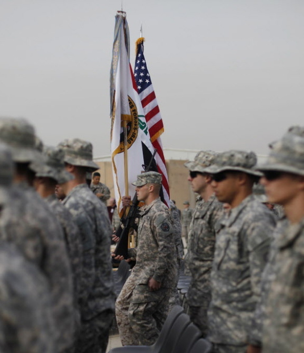 The American flag, Iraqi flag, and the U.S. Forces Iraq colors are carried during ceremonies in Baghdad today marking the end of the U.S. military mission in Iraq.