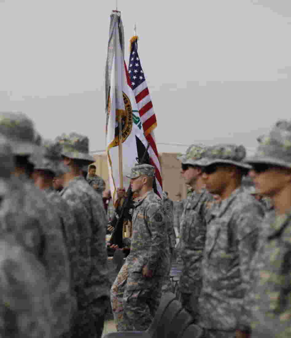 The American flag, Iraqi flag, and the U.S. Forces Iraq colors are carried during ceremonies in Baghdad today marking the end of the U.S. military mission in Iraq.