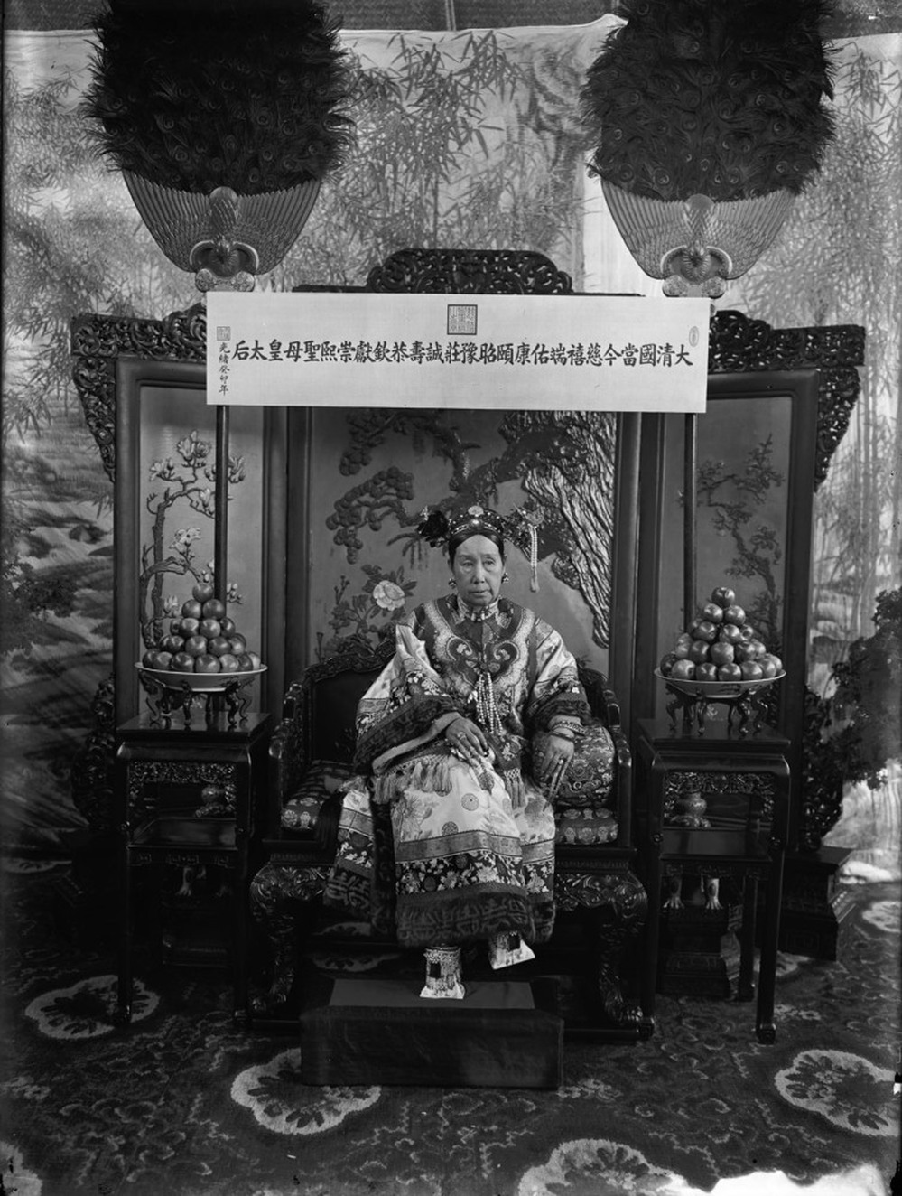 This photograph is one of a series of photos that shows Cixi seated on her throne in front of a banner that declares her full title. Click here to see a close-up of her "horse-hoof" platform shoes.