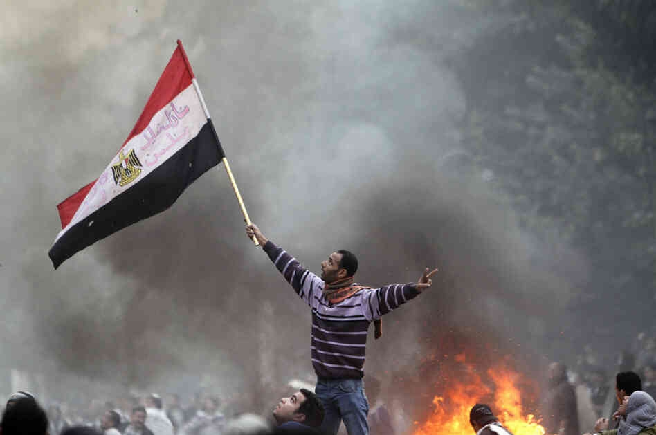 An Egyptian protester waves his national flag while making the victory sign outside the parliament building during clashes with soldiers near Cairo's Tahrir Square on Friday. An Egyptian protester waves his national flag while making the victory sign outside the parliament building during clashes with soldiers near Cairo's Tahrir Square on Friday.