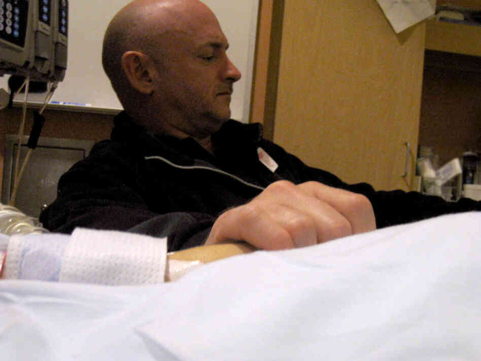 Mark Kelly holds his wife's hand in her hospital room on Jan. 9 in Tucson, Ariz., the day after she was shot. He has had to make critical choices about her care. "The key," he tells NPR's Neal Conan, "is knowing what requires a quick decision and what you can put off, and try to gather more information and decide later."