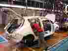 A worker installs components into a Leaf electric vehicle at the company's plant in Kanagawa, Japan. 