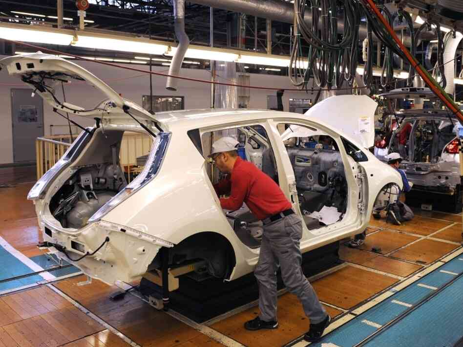 A worker installs components into a Leaf electric vehicle at the company's plant in Kanagawa, Japan. 