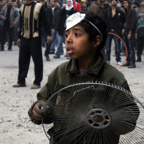 A youthful protester holds a fan cover to protect himself from rocks during clashes with military police near Tahrir Square in Cairo on Friday.