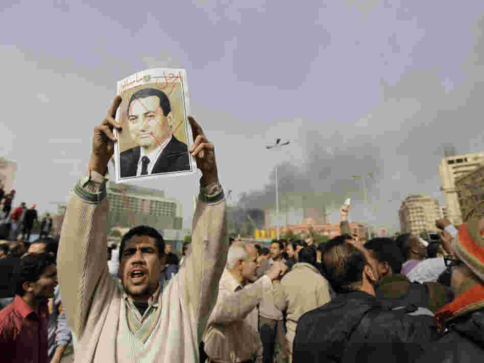 An Egyptian anti-government protester holds a defaced poster of Egyptian President Hosni Mubarak, with the words "Mubarak, get out" written above, during a demonstration in Cairo in January. 
