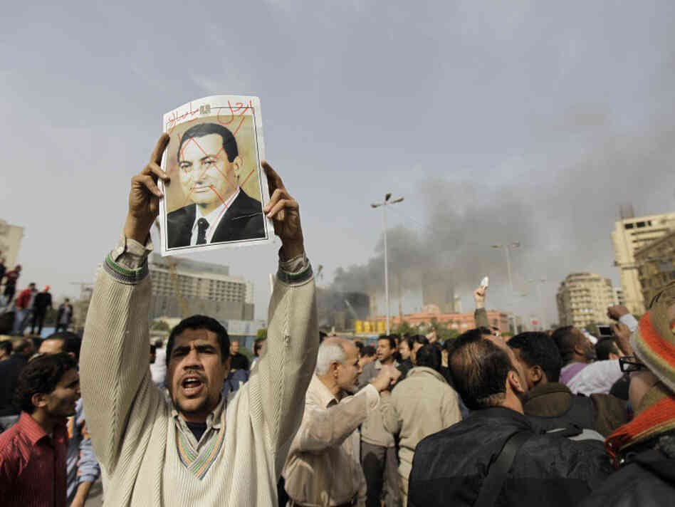 An Egyptian anti-government protester holds a defaced poster of Egyptian President Hosni Mubarak, with the words "Mubarak, get out" written above, during a demonstration in Cairo in January. 