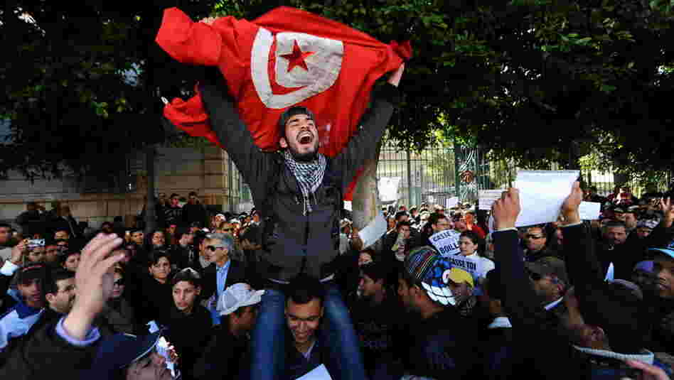 Tunisians protest outside the gates to the French Embassy in Tunis. Arab Spring began in Tunisia when a fruit vendor set himself on fire in protest in front of a government building.