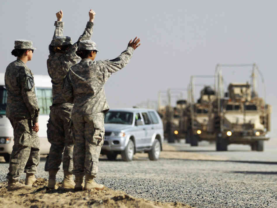 Soldiers wave to the last American military convoy to depart Iraq after it crosses over the border into Kuwait on Sunday.