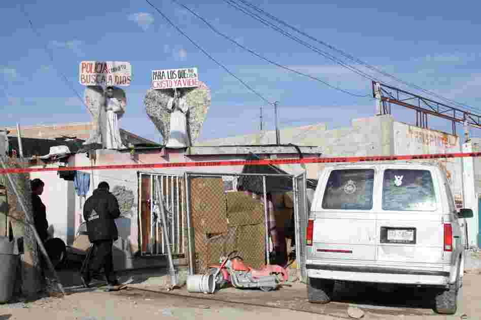 Messenger angels hold signs on a rooftop near a recent murder site. Police and investigators are on the scene, although murders are rarely solved in Ciudad Juarez.