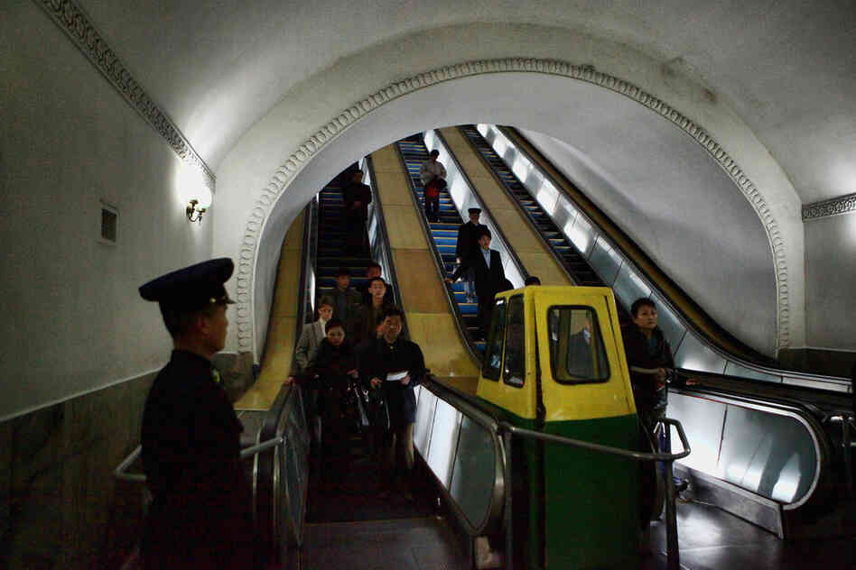 Commuters move by escalator at Puhung Subway station.
