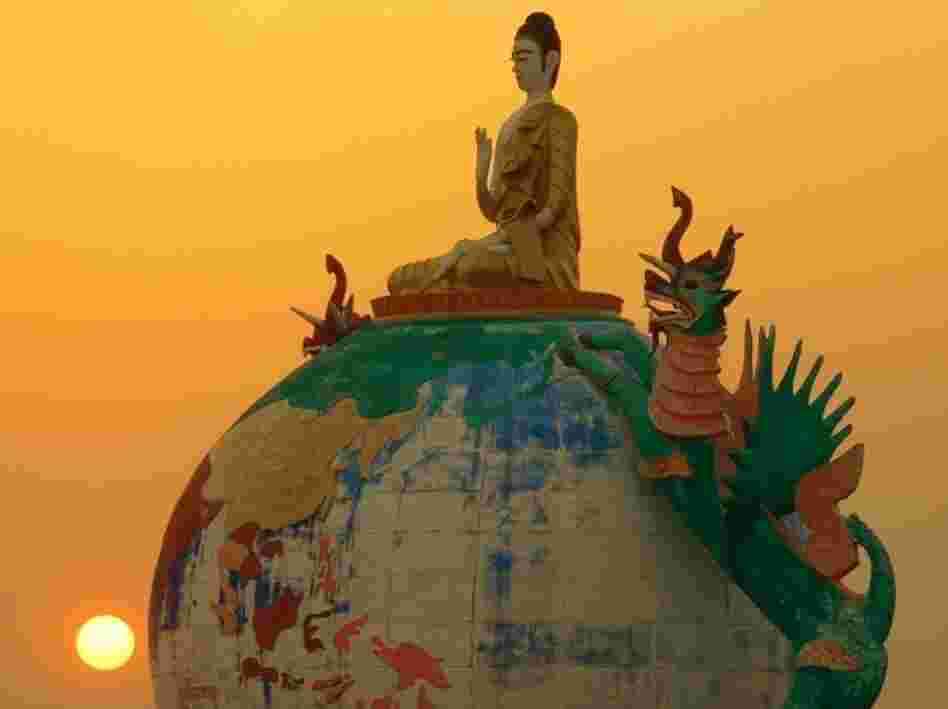 A globe Buddha is visible against the sunset in Myanmar, also known as Burma.