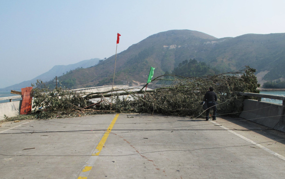 The Chinese national flag rises over villagers' barricades in Wukan. Tree trunks and broken glass are strewn in the road in an attempt to prevent authorities from moving in.