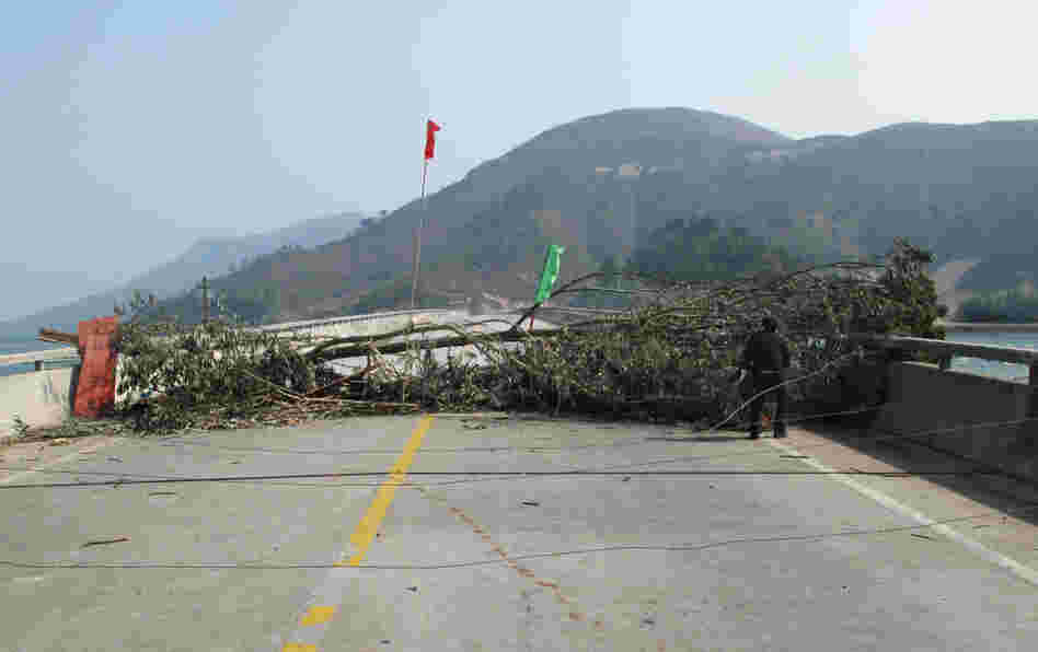 The Chinese national flag rises over villagers' barricades in Wukan. Tree trunks and broken glass are strewn in the road in an attempt to prevent authorities from moving in.