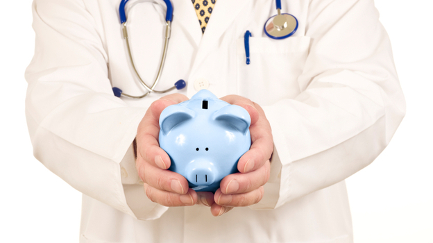 A doctor holds a piggy bank.