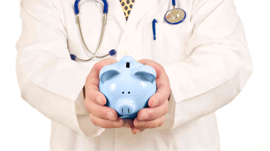 A doctor holds a piggy bank.