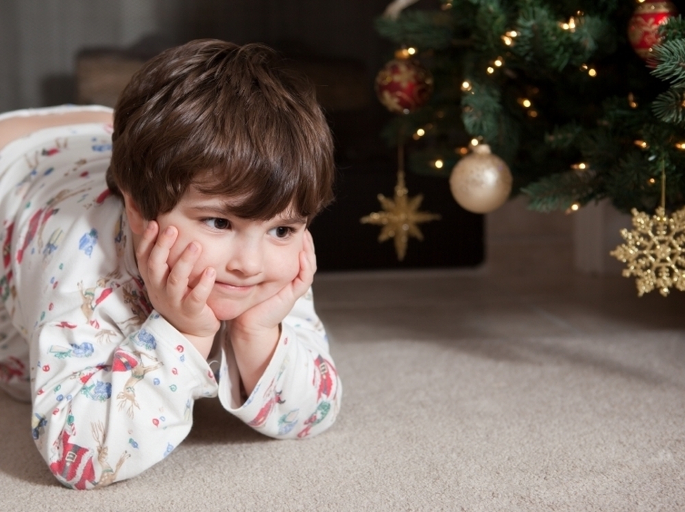 A child sits in anticipation near a Christmas tree