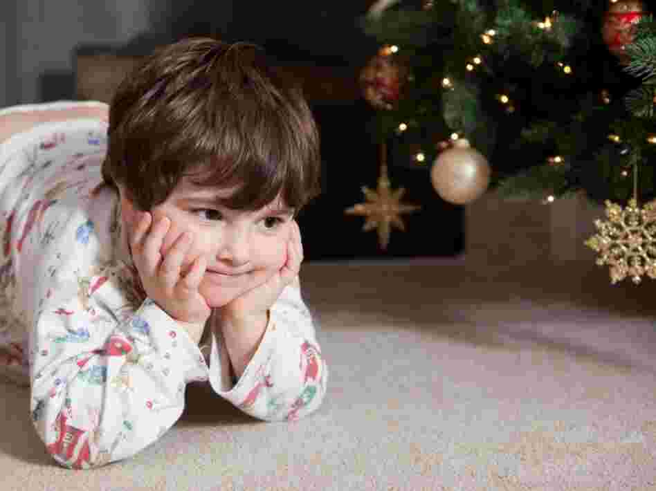 A child sits in anticipation near a Christmas tree