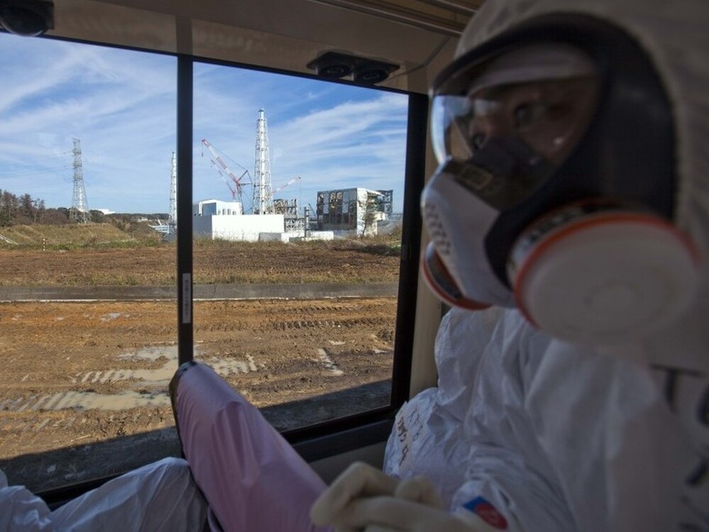 An official from the Tokyo Electric Power Co. (right), wearing a protective suit and mask, rides on a bus taking journalists by the crippled Fukushima nuclear power station in northeast Japan in November. Japanese officials say the plant is stable, but concerns about radioactivity remain a constant worry in many parts of Japan.