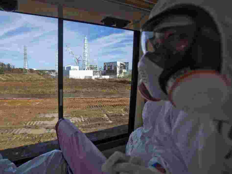 An official from the Tokyo Electric Power Co. (right), wearing a protective suit and mask, rides on a bus taking journalists by the crippled Fukushima nuclear power station in northeast Japan in November. Japanese officials say the plant is stable, but concerns about radioactivity remain a constant worry in many parts of Japan.